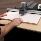 Hands guiding cabinet panel under drilling head for pocket joinery