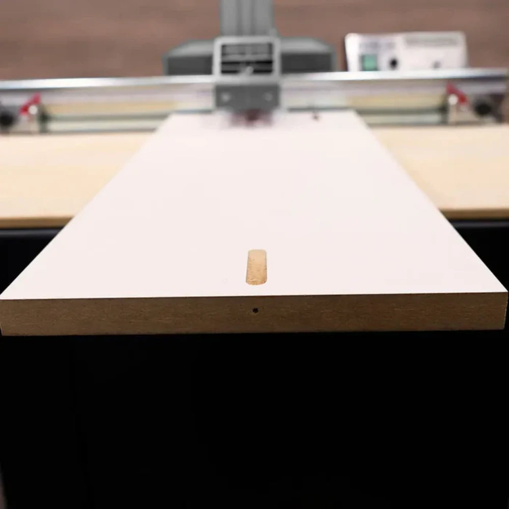 Worker feeding long board through pocket hole machine table